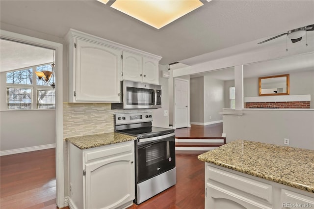 kitchen featuring stainless steel appliances, light stone countertops, white cabinets, and decorative backsplash