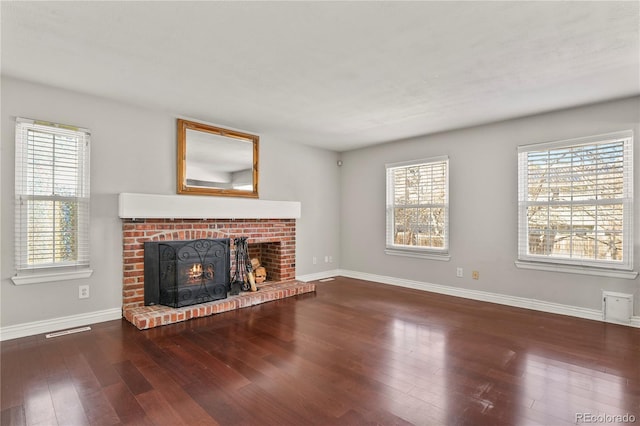 unfurnished living room with a brick fireplace, wood-type flooring, and a healthy amount of sunlight