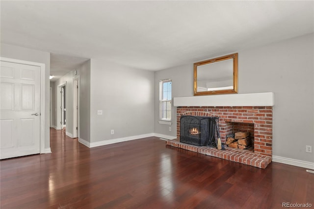 unfurnished living room featuring dark hardwood / wood-style floors and a brick fireplace