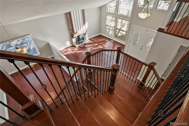 stairway with wood-type flooring and high vaulted ceiling