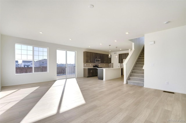 unfurnished living room with light wood-type flooring and sink