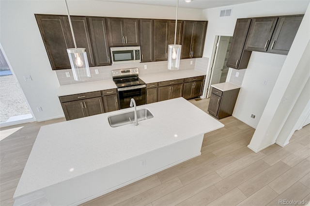 kitchen with backsplash, stainless steel appliances, sink, decorative light fixtures, and light hardwood / wood-style floors