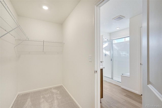 walk in closet with light hardwood / wood-style floors