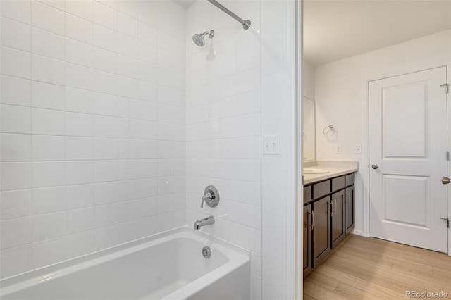 bathroom with hardwood / wood-style flooring, vanity, and tiled shower / bath combo