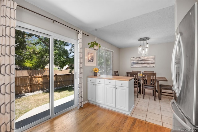 944 E Lily Ct, Highlands Ranch, CO 80126 - kitchen featuring freestanding refrigerator, white cabinetry, pendant lighting, a chandelier, and a textured ceiling