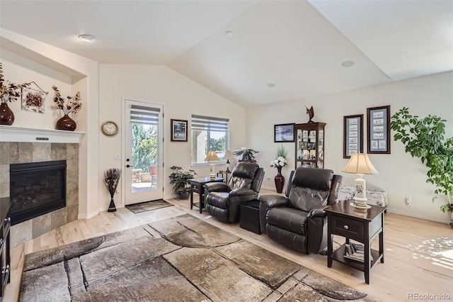 living room with lofted ceiling, light hardwood / wood-style flooring, and a tile fireplace