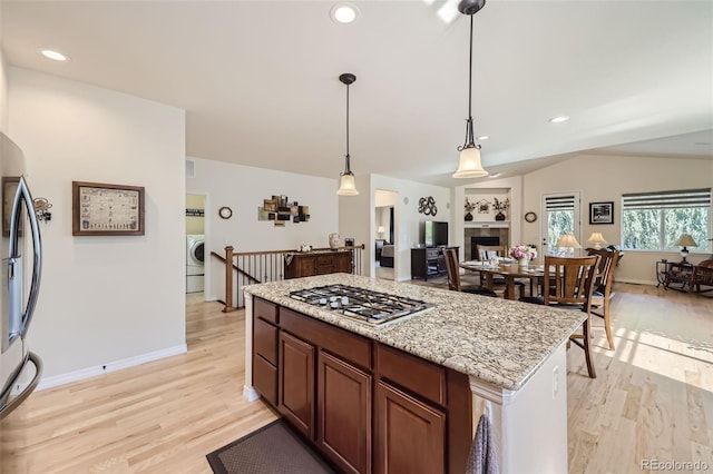 kitchen featuring lofted ceiling, hanging light fixtures, appliances with stainless steel finishes, and light wood-type flooring