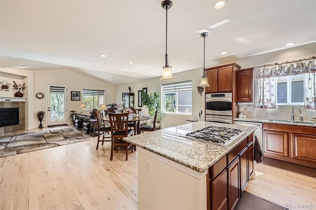 kitchen featuring appliances with stainless steel finishes, light wood-type flooring, vaulted ceiling, and sink