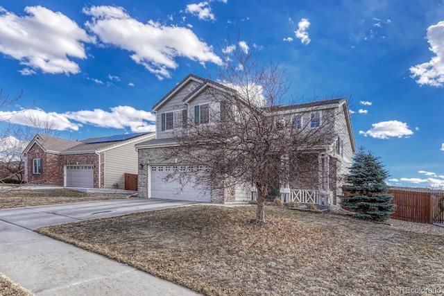 traditional home with a garage, fence, and concrete driveway