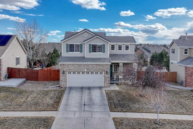 traditional-style house featuring driveway, brick siding, an attached garage, and fence