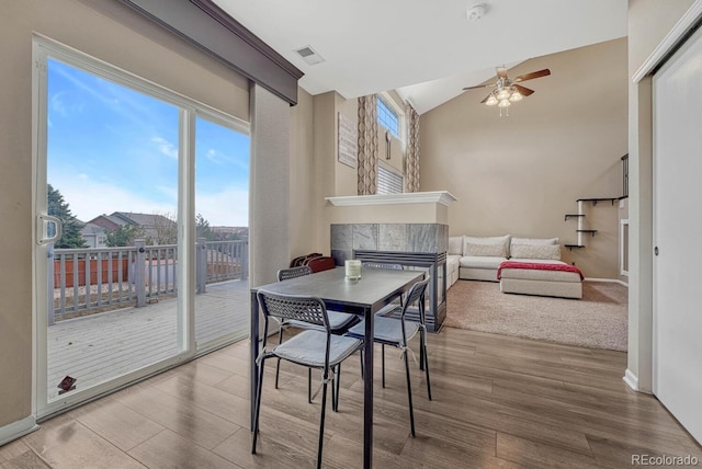 dining space featuring baseboards, visible vents, ceiling fan, wood finished floors, and a fireplace