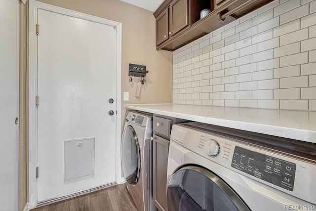 laundry room with dark wood-style flooring, cabinet space, and separate washer and dryer