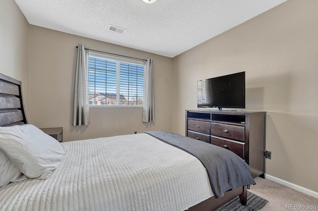 carpeted bedroom featuring visible vents, baseboards, and a textured ceiling