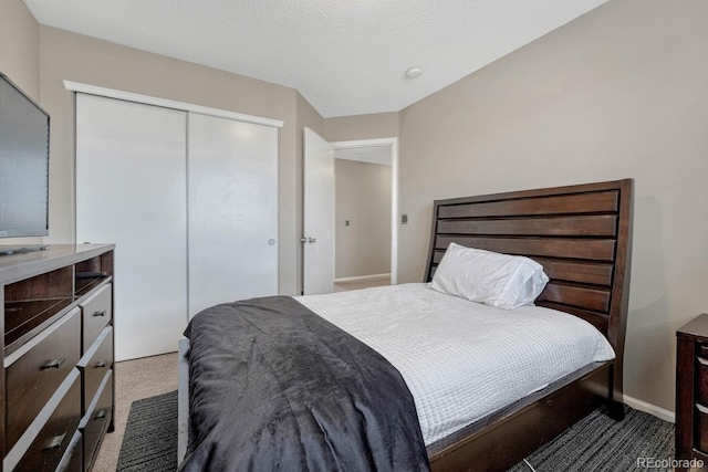 bedroom featuring carpet floors, a closet, a textured ceiling, and baseboards