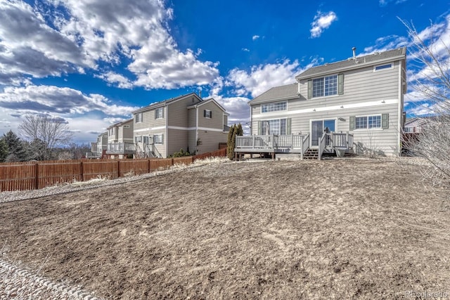 rear view of house with a deck and fence