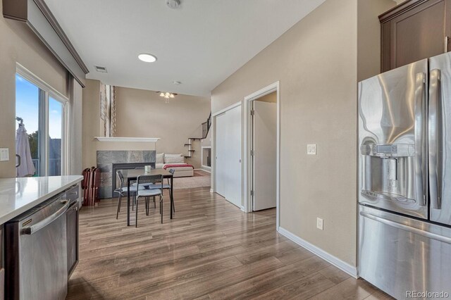 kitchen with wood finished floors, light countertops, stainless steel appliances, a fireplace, and visible vents