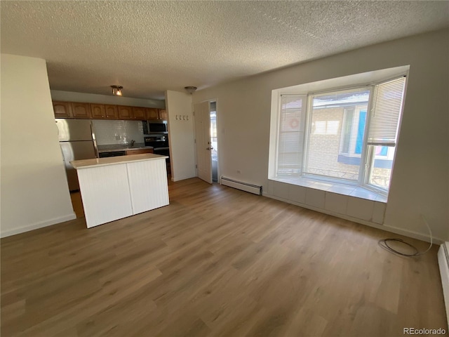 kitchen featuring a baseboard heating unit, light wood-type flooring, a textured ceiling, and appliances with stainless steel finishes