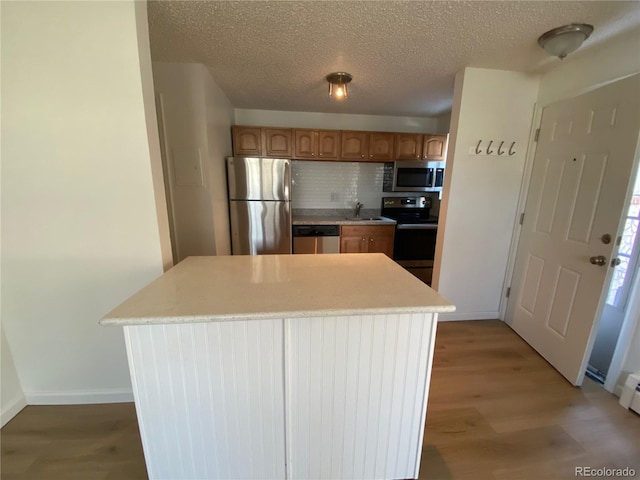 kitchen featuring sink, tasteful backsplash, a center island, hardwood / wood-style flooring, and stainless steel appliances