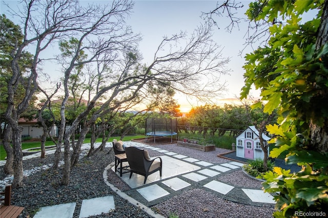 725 Nebula Ct, Colorado Springs, CO 80906 - patio terrace at dusk with a trampoline, a patio, and a fenced backyard