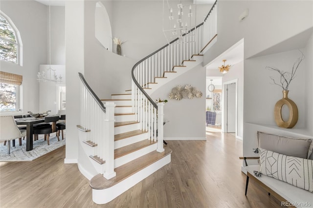 725 Nebula Ct, Colorado Springs, CO 80906 - staircase featuring a high ceiling, plenty of natural light, a chandelier, and wood finished floors