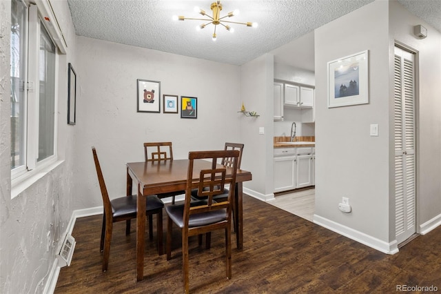 1060 S Parker Rd Unit 19, Denver, CO 80231 - dining space featuring a chandelier, a textured ceiling, wood finished floors, and baseboards