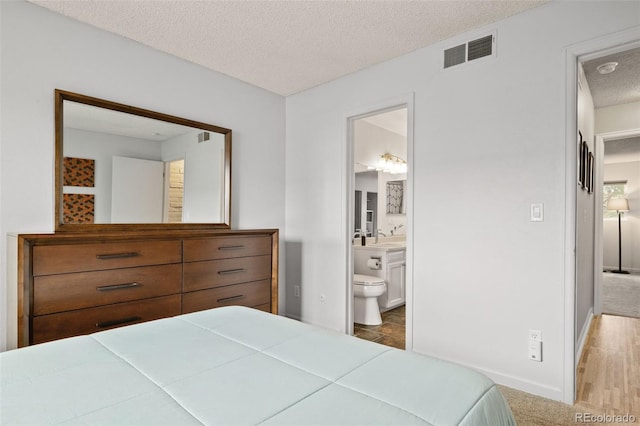 1060 S Parker Rd Unit 19, Denver, CO 80231 - bedroom featuring a textured ceiling, a sink, baseboards, and connected bathroom