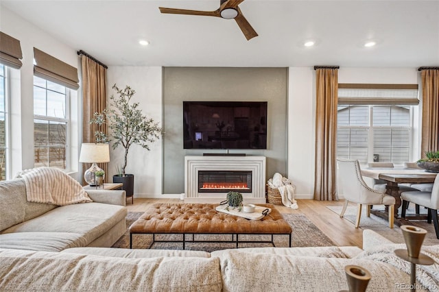 living room featuring baseboards, a glass covered fireplace, wood finished floors, and recessed lighting