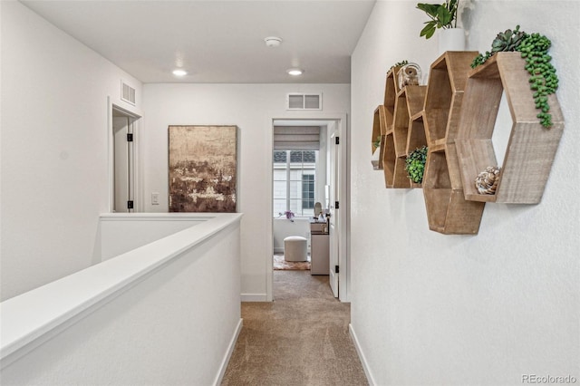 hall with carpet, visible vents, baseboards, and an upstairs landing