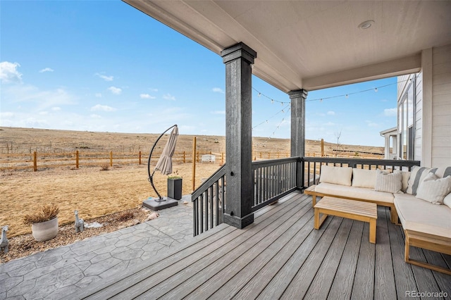 wooden deck with a rural view, fence, and an outdoor living space