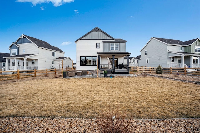 rear view of property featuring a fenced backyard, a lawn, board and batten siding, and a patio