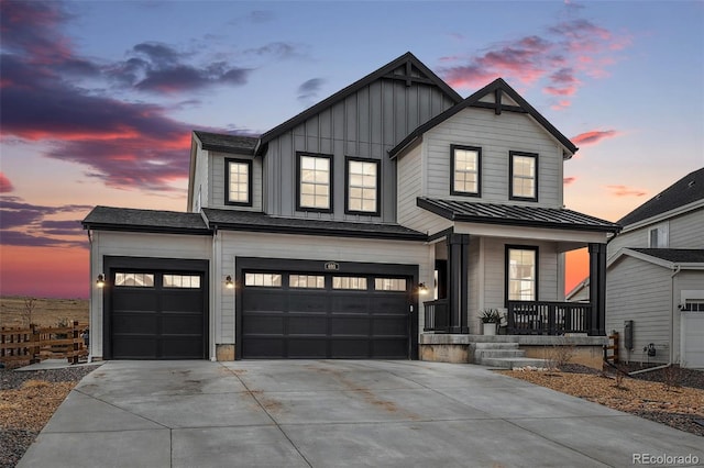 modern farmhouse with board and batten siding, covered porch, a standing seam roof, and concrete driveway