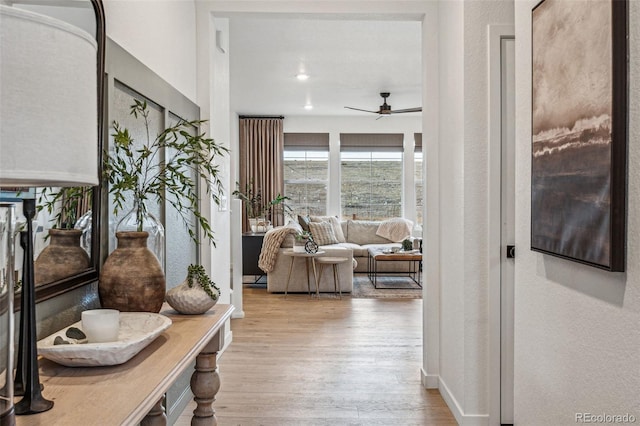 hallway featuring a textured wall, wood finished floors, and recessed lighting