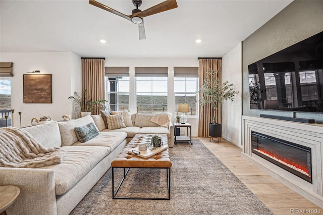 living room with a ceiling fan, a glass covered fireplace, recessed lighting, and wood finished floors