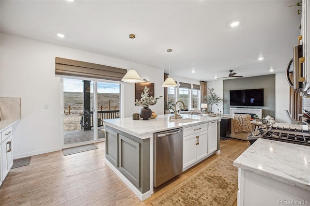 kitchen with a sink, light wood-style floors, white cabinets, light stone countertops, and dishwasher