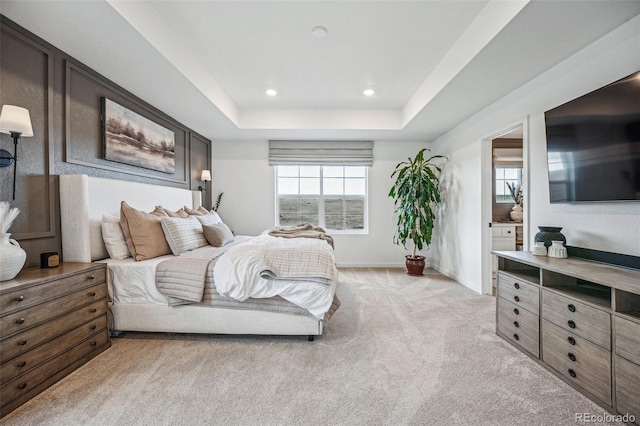 bedroom with light carpet, recessed lighting, a raised ceiling, and baseboards