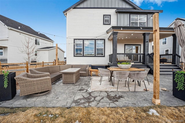 back of property featuring board and batten siding, a patio area, fence, and an outdoor hangout area