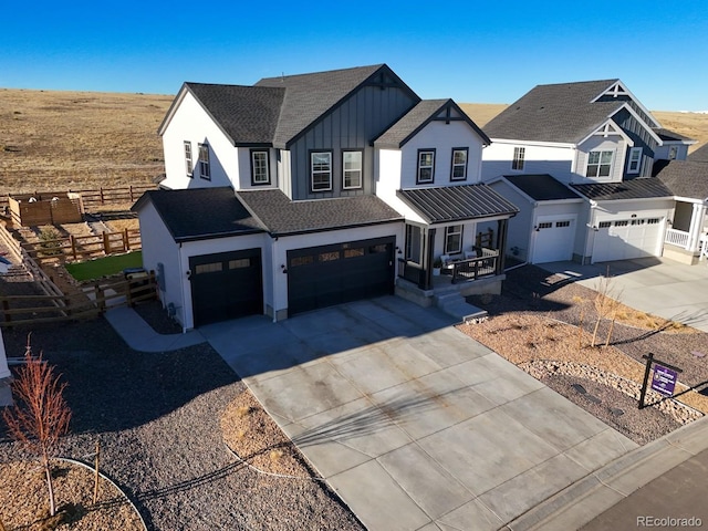 modern farmhouse featuring a garage, driveway, fence, a porch, and board and batten siding