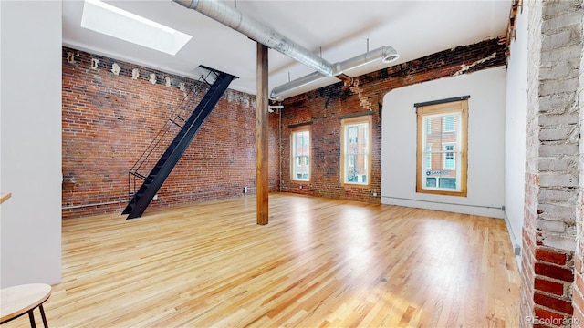 1510 Wazee St Unit 3, Denver, CO 80202 - unfurnished living room with brick wall, wood finished floors, and a skylight