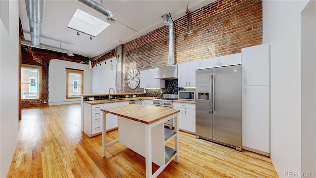 1510 Wazee St Unit 3, Denver, CO 80202 - kitchen featuring stainless steel appliances, a skylight, butcher block countertops, a peninsula, and light wood finished floors