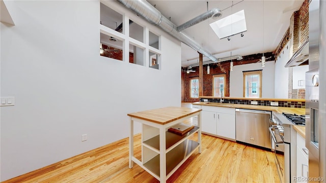 1510 Wazee St Unit 3, Denver, CO 80202 - kitchen featuring appliances with stainless steel finishes, a skylight, light wood-type flooring, and a peninsula