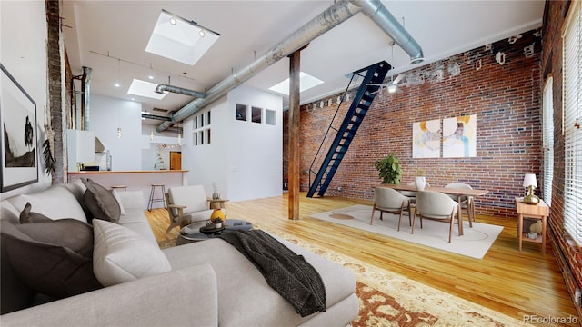 1510 Wazee St Unit 3, Denver, CO 80202 - living room featuring brick wall, wood finished floors, a skylight, a high ceiling, and stairs