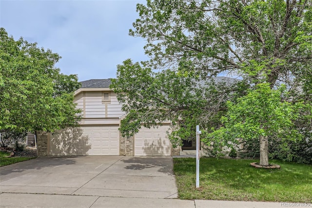 2307 S Ensenada St, Aurora, CO 80013 - view of property hidden behind natural elements with concrete driveway, a front yard, an attached garage, and brick siding