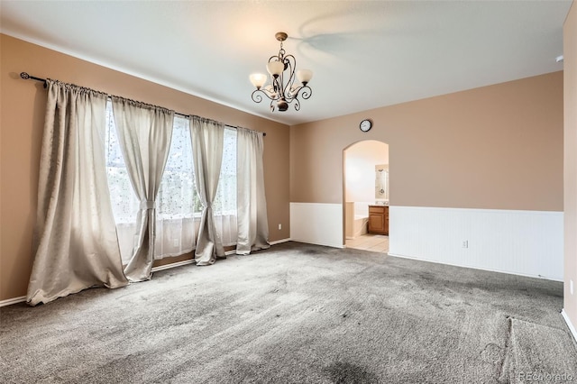 2307 S Ensenada St, Aurora, CO 80013 - unfurnished room featuring arched walkways, light colored carpet, wainscoting, and a chandelier