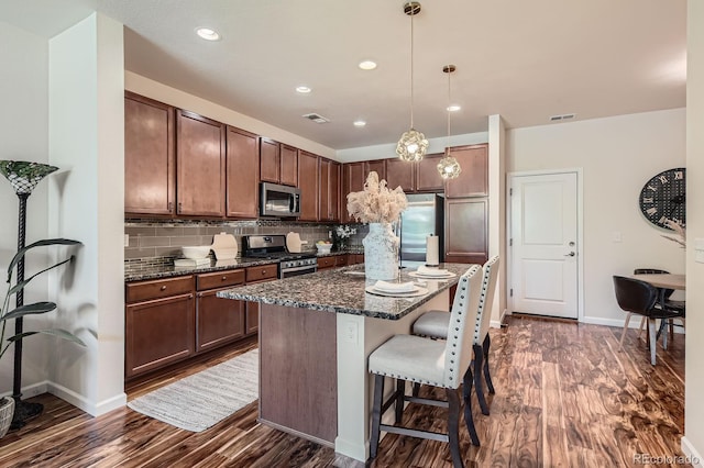 504 E Dry Creek Pl, Littleton, CO 80122 - kitchen featuring appliances with stainless steel finishes, dark wood-type flooring, a kitchen bar, decorative backsplash, and baseboards