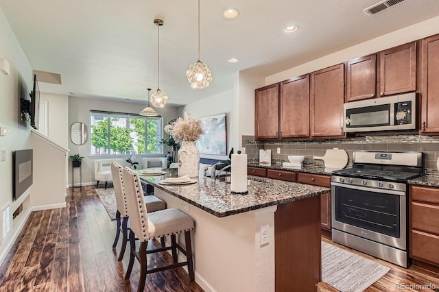 504 E Dry Creek Pl, Littleton, CO 80122 - kitchen featuring stainless steel appliances, a sink, dark stone countertops, dark wood-type flooring, and decorative backsplash