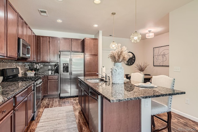 504 E Dry Creek Pl, Littleton, CO 80122 - kitchen featuring stainless steel appliances, a kitchen breakfast bar, a sink, dark wood-type flooring, and a center island with sink