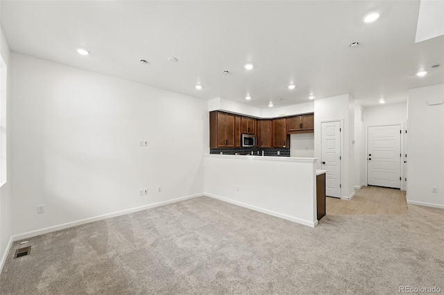 17117 W 91st Ln, Arvada, CO 80007 - kitchen featuring light colored carpet, stainless steel microwave, baseboards, recessed lighting, and a peninsula