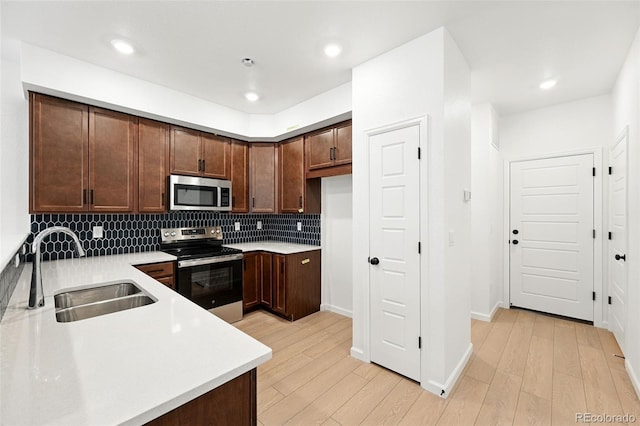 17117 W 91st Ln, Arvada, CO 80007 - kitchen featuring appliances with stainless steel finishes, a sink, light wood-style floors, light countertops, and recessed lighting
