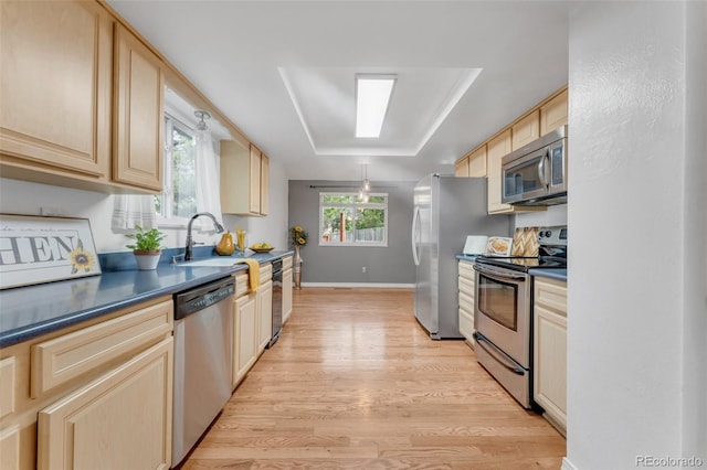 445 Wintery Cir, Colorado Springs, CO 80919 - kitchen featuring appliances with stainless steel finishes, light wood-style floors, a sink, light brown cabinets, and dark countertops