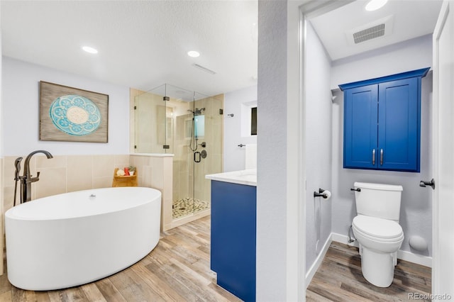 445 Wintery Cir, Colorado Springs, CO 80919 - full bath with wood finished floors, a stall shower, a soaking tub, toilet, and tile walls